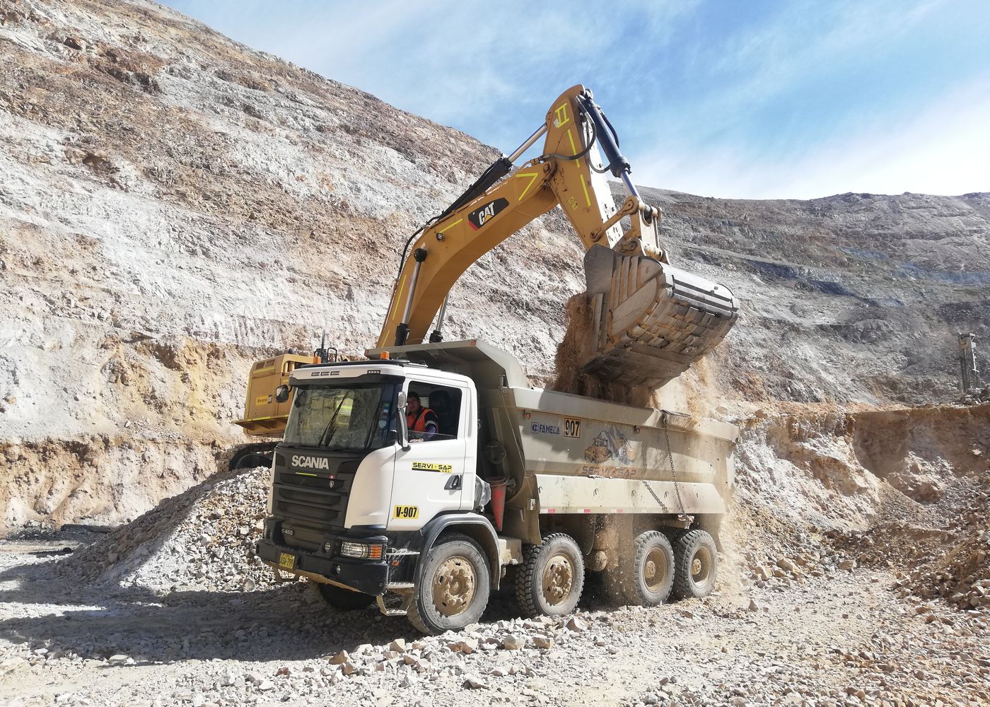 Construction site inspection plan: excavator loading a dump truck. Illustrative stock photo.