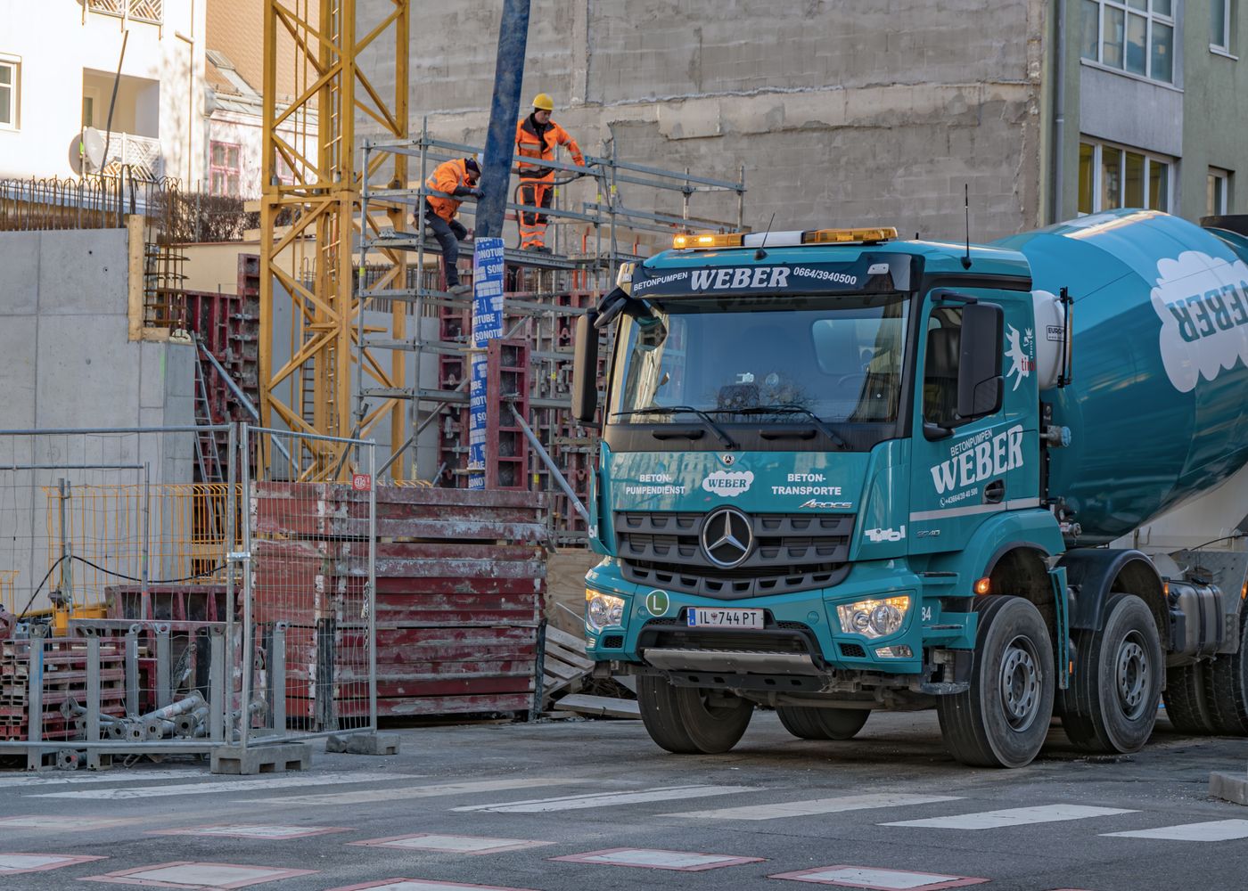 Mixer drum drive test: mixer truck and workers on construction site. Illustrative stock photo.